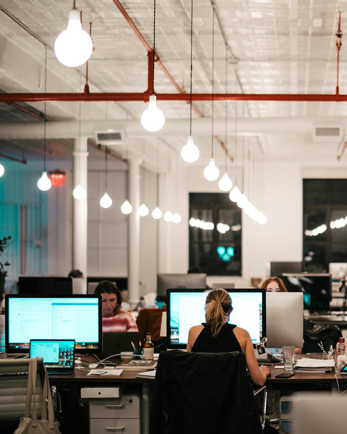 Open-plan office in the evening, screens on